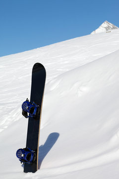 Snowboard in snowdrift and mountains at nice sun day