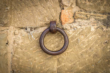 old iron ring a little rusty embedded in a stone wall, used to leave tethered animals like horses or mules