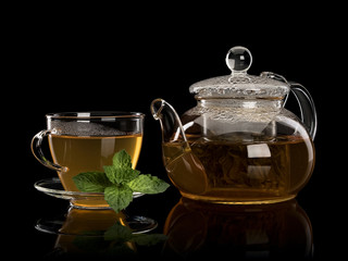 Fresh mint and green tea in a cup and a teapot from glass