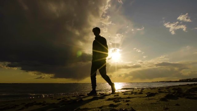 Man walking on the beach, beautiful sunset on the sea. Slow motion.