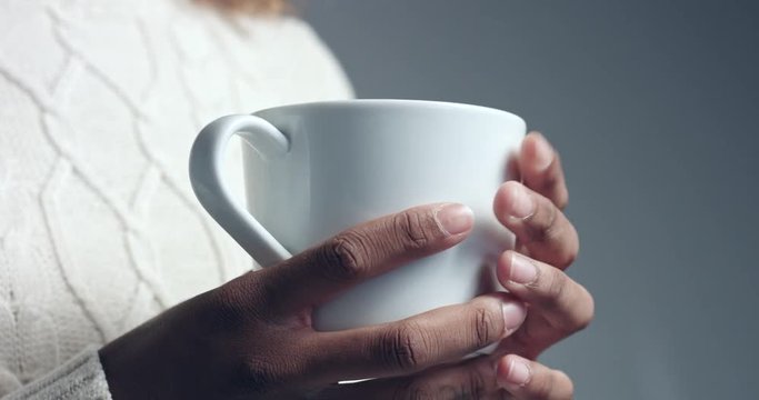 Black woman with white cup  of hot drink holding it and turning it