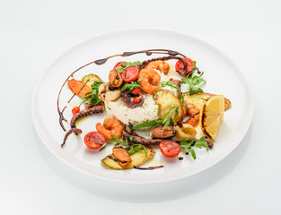 The seafood fried with ricotta on a white plate. Decorated with goji and ruccola.