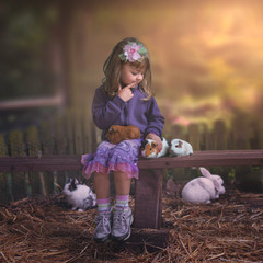 Little girl in the farm with guinea pigs and rabbits