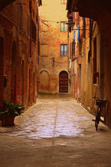 A small narrow street in Siena without people. The bicycle is standing on the street