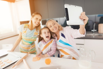 Selfi on the tablet. An elderly woman decided to make a selfie with her daughter and granddaughter