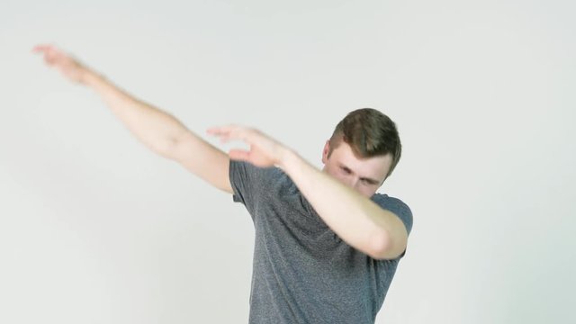 Young man makes a dab or flex it's dance move on white background