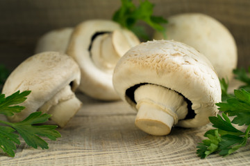 White mushrooms champignons, parsley, old wooden table