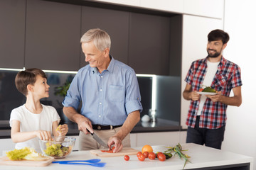 The old man and the boy are preparing a salad. The boy's father brought them more vegetables