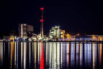 Waterfront factory at night with colorful lights