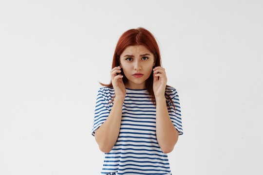 Body language. Picture of beautiful anxious worried young woman in striped t-shirt touching her face, frowning and staring at camera. Anxiety, worry, stress, frustration and negative feelings