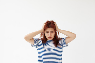 Angry stressful student girl in striped t-shirt tearing hair on her head, feeling anxious and nervous because of problems at college. Negative human expressions, emotions, feelings and attitude