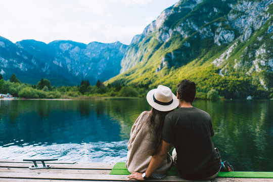 Rear view of couple sitting on pier by lake