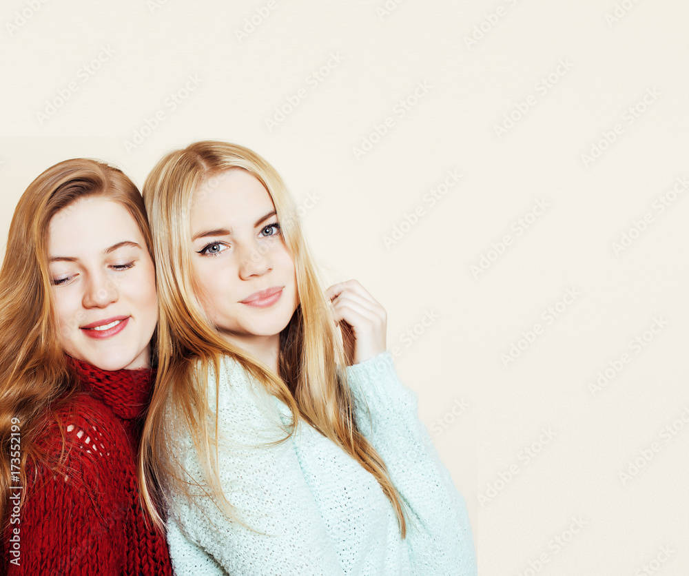 Wall mural Two young girlfriends in winter sweaters indoors having fun. Lif