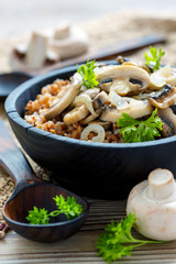 Buckwheat porridge with mushrooms in a wooden bowl.