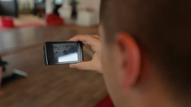 Man filming breakdance performance on his smartphone, leisure activities