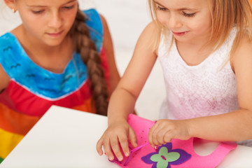 Obraz na płótnie Canvas Older sister supervising a little girl on crafting project