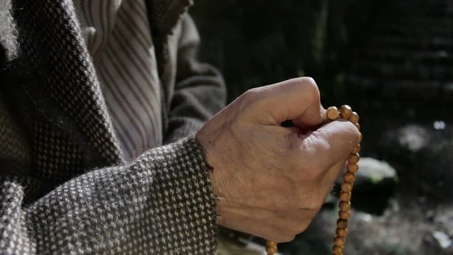 Old man holding prayer beads in hand