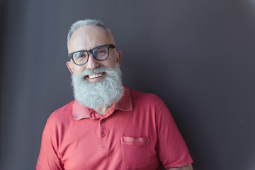 Cheerful old male in glasses is standing with smile