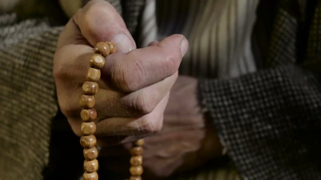 Old man holding prayer beads in hand