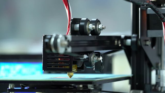 working 3D printer prints the mechanical part is made of red plastic