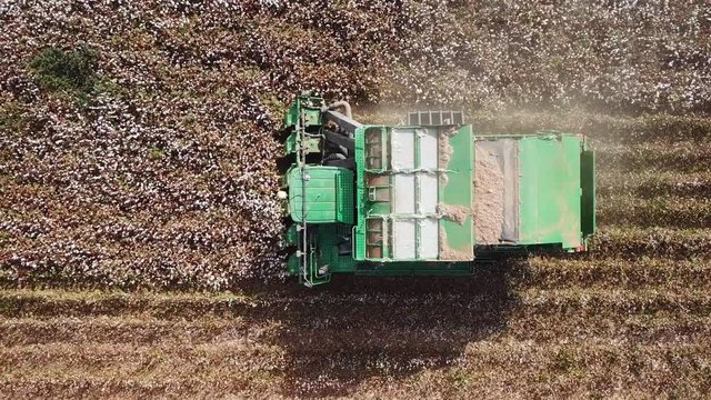 Aerial view of a Large green Cotton picker working in a field.