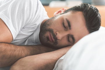 Fototapeta na wymiar Calm man enjoying dreams while lying on bed