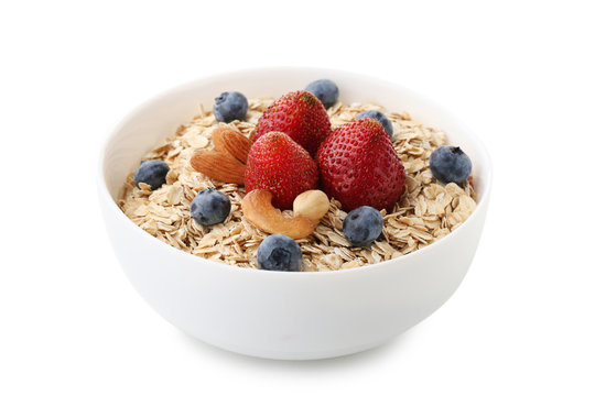 Oat flakes in bowl with berries and nuts isolated on white