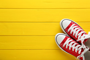 Pair of red sneakers on yellow wooden table