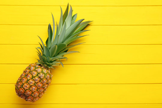 Ripe pineapple on yellow wooden table