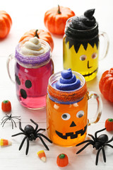 Halloween jelly in glass jars with candies on white wooden table