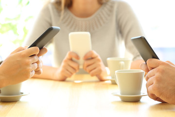 Three friends using their smart phones in a bar