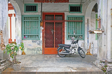Fototapeta na wymiar Quintessential Malaysia doorway scene with motorbike, typical across SE Asia, as seen in Penang