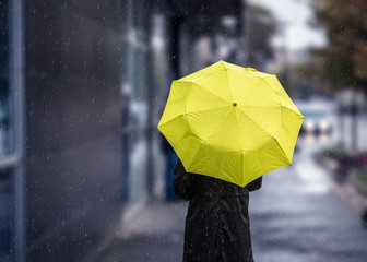 Woman walking on rainy day with yellow umbrella
