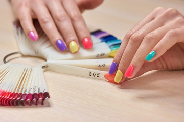 Obraz na płótnie Canvas Female hand holding nails colors samples. Womans summer shellac nails. Choice summer fashion manicure.