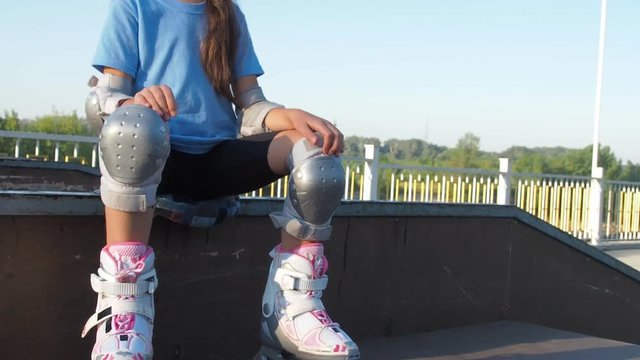 Little girl is sitting in roller skates. Girl in white roller skates.