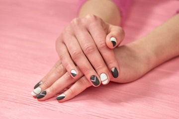 Obraz na płótnie Canvas Girls hands with black and white manicure. Female hands with classic colors manicure on salon table. Nail care and treatment.