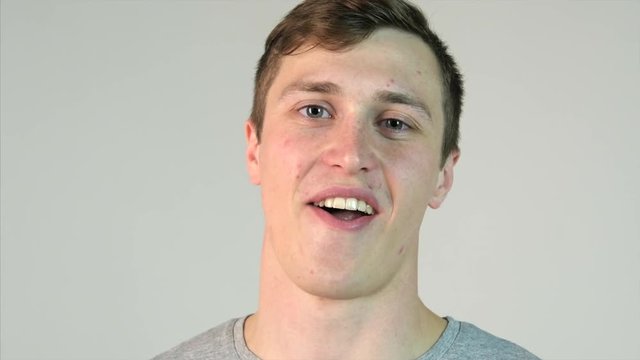 Young man chews gum on white background. Chewing gum in the man's mouth. Beautiful guy chews gum