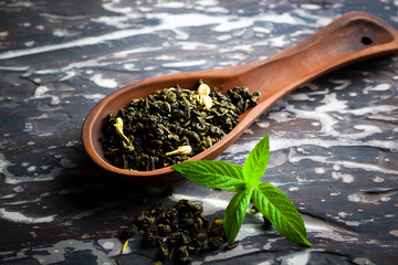 Dry tea leaves in a spoon on an old background
