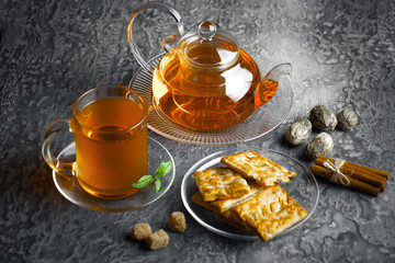 Tea in a cup on a metallic background in a composition with a cookware