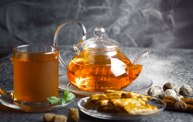 Tea in a cup on a metallic background in a composition with a cookware