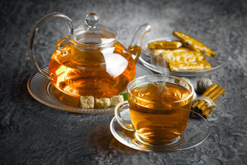 Tea in a cup on a metallic background in a composition with a cookware