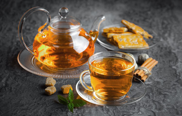 Tea in a cup on a metallic background in a composition with a cookware