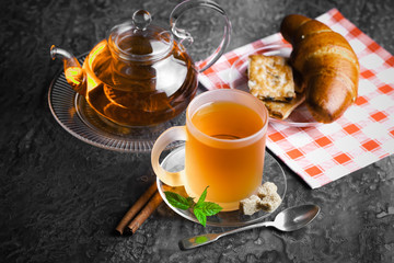 Tea in a cup on a metallic background in a composition with a cookware