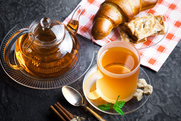 Tea in a cup on a metallic background in a composition with a cookware