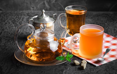 Tea in a cup on a metallic background in a composition with a cookware