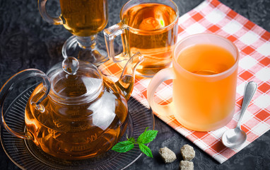 Tea in a cup on a metallic background in a composition with a cookware