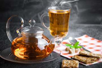 Tea in a cup on a metallic background in a composition with a cookware