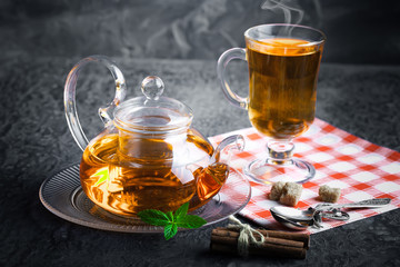 Tea in a cup on a metallic background in a composition with a cookware