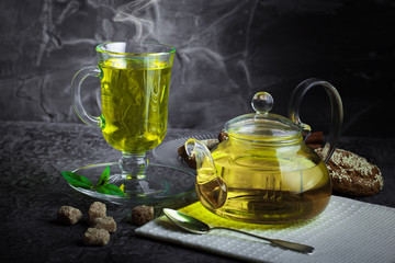Tea in a cup on a metallic background in a composition with a cookware