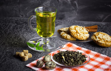 Tea in a cup on a metallic background in a composition with a cookware